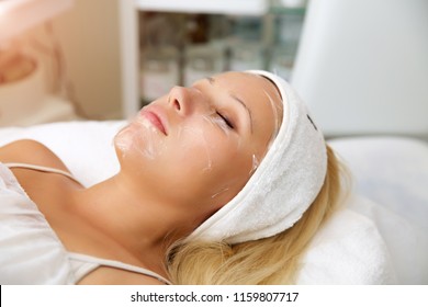 Process Cosmetic Mask Of Massage And Facials In Beauty Salon. Cosmetologist Removes Dead Skin Cells.