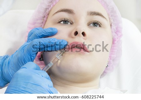 The process of cosmetic surgery of water injection in the area of the lips of a woman
