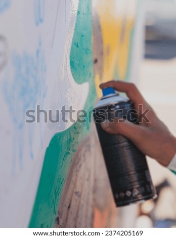 Process of creating graffiti, street artist with aerosol spray paint painting colorful stencil murals on the city walls, equipment set for drawing street art grafiti, paint can, brush and roller