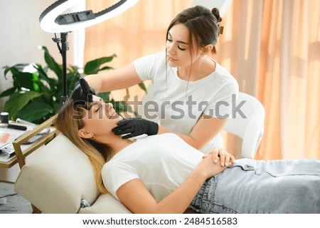 Process of creating permanent brow makeup with a machine at beauty salon.