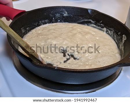 Process of creating a roux out of flour and butter in a cast iron skillet on a stove top