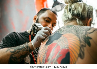 the process of creating a tattoo on the back of a girl. Professional tattoo. Carp Fish tattoo