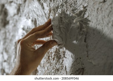 Process of creating white textured clay wall with cracks and imperfections using sstones. Wall design ideas in contemporary interior. 