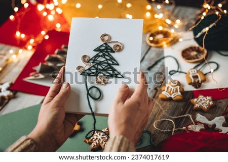 Process of creation of handmade Christmas card with wool thread embroidering on the craft recycled paper. Sustainable lifestyle, zero waste, personal gift. Family time, leisure activity, hobby