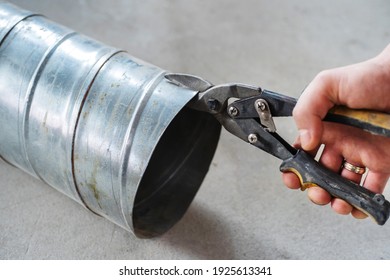 The process of cutting a chimney pipe with metal scissors. Close-up