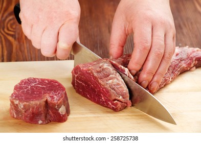 The Process Of Cutting Raw Beef On A Cutting Board Closeup