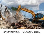 Process of demolition of old building dismantling. Excavator breaking house. Destruction of dilapidated housing for new development