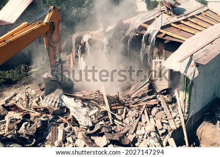 Process of demolition of old building dismantling aerial view. Excavator breaking house. Destruction of dilapidated housing for new development