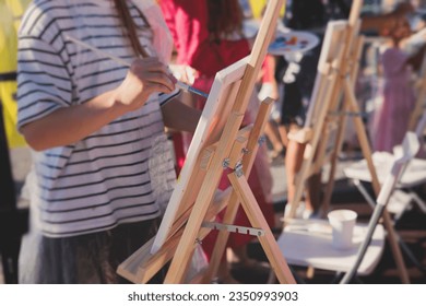 Process of drawing, group class of talented students with painting easels and canvases during lesson of watercolour painting outdoors, drawing class for adult artists in art school