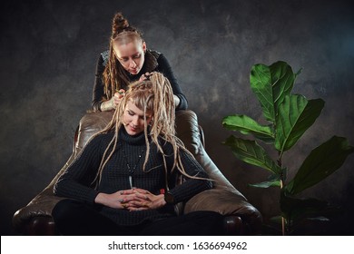 Process of dreadlocks making - female master is working on girl's hair.