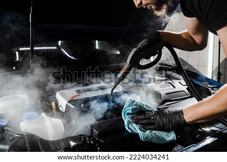 Process of drying car engine after washing with water and chemical detergent. Detailing cleaning motor from dust and dirt