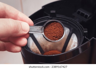 The process of filter coffee preparation. Portion of ground coffee spilled in electrical dripper. Closeup view with selective focus on spoon. - Powered by Shutterstock