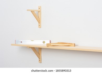 The Process Of Fixing The Wooden Shelf To The Wall, The Level Tool Checks The Evenness Of The Shelf