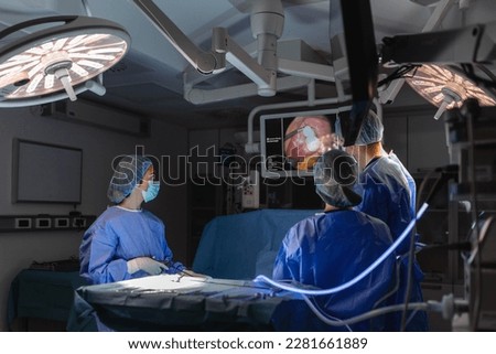 Process of gynecological surgery operation using laparoscopic equipment. Group of surgeons in operating room with surgery equipment. Background
