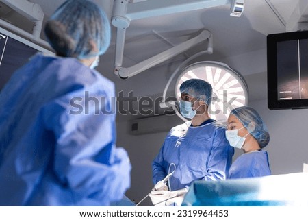Process of gynecological surgery operation using laparoscopic equipment. Group of surgeons in operating room with surgery equipment. Background
