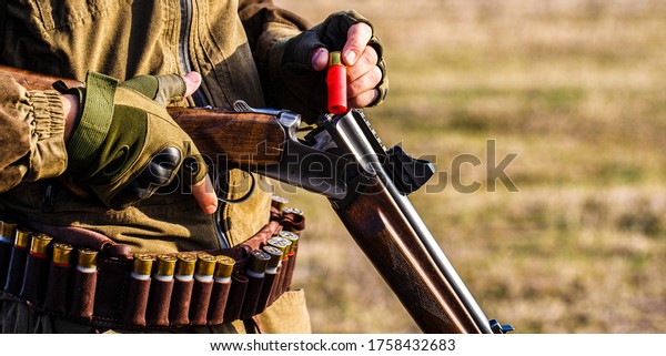Process of hunting during\
hunting season. Male hunter in ready to hunt. Closeup. Hunter man.\
Hunting period. Male with a gun, rifle. Man is charging a hunting\
rifle. 