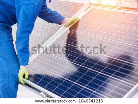 Process of installation solar batteries in winter. Worker in blue uniform and gloves. Close-up