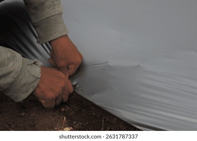 the process of installing black silver mulch on new beds