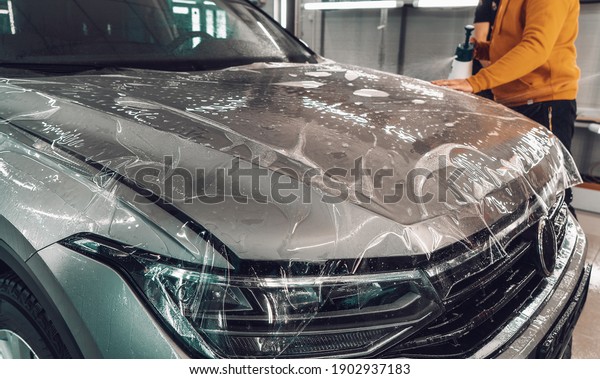 Process of installing of Paint Protection Film or\
PPF on new car in professional auto Detailing Center. Thin\
polyurethane film or polymer as protective skin from scratches and\
rock chips