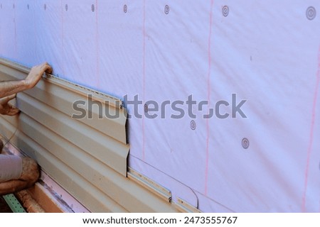 In process of installing vinyl siding on new home facade, handyman installs vinyl PVC siding