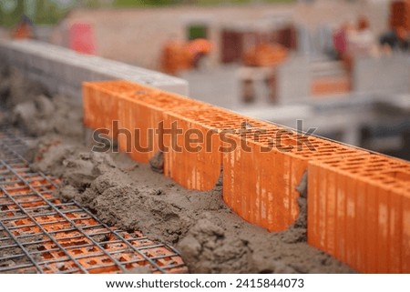 Process of laying red brick wall at construction site.