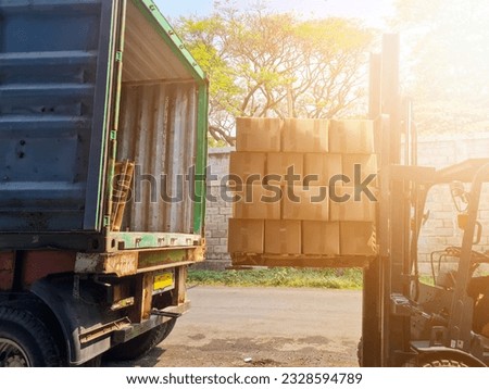 The process of loading carton boxes with forklift tractors on pallets to cargo containers.  Trailer truck parked loading in loading dock warehouse.  Shipping delivery.  supply chain concept.