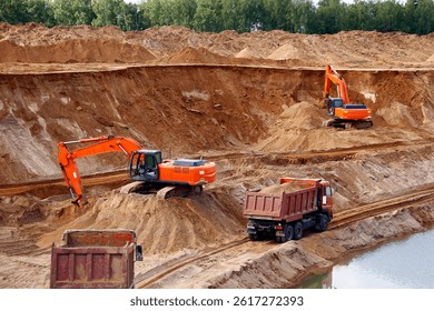 The process of loading sand into trucks at a quarry is a mining operation. Excavators and heavy trucks are involved in this process