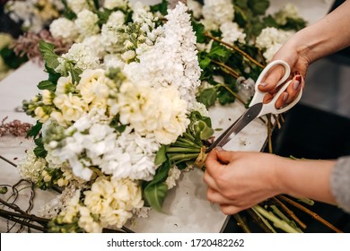 Process of making a bouquet of seasonal white flowers. Female florist making bouquet in flower shop using scissors. - Powered by Shutterstock