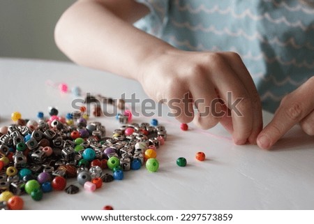 Process of making a bracelet from a thread and colored beads, concept of hobby or leisure