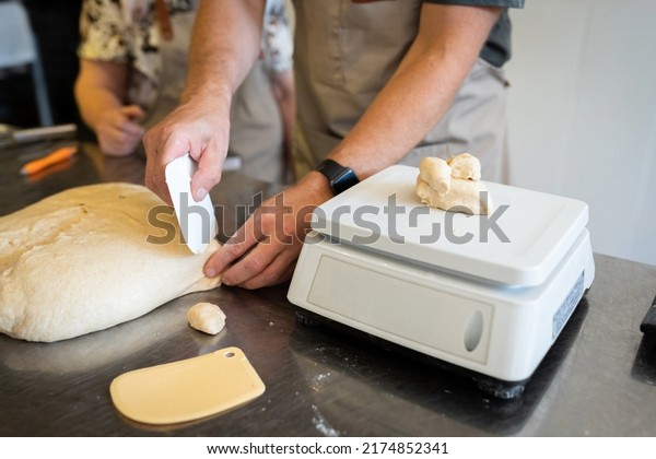 The process of making bread. Dividing\
the wheat dough into pieces for buns. Front\
view.