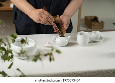 The Process Of Making Chinese Tea. Someone Puts Tea Leaves In A Ceramic Teapot. Blurred Background