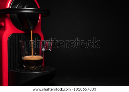 Process of making coffee by coffee machine into glass transparent cup - espresso coffee coming out from an automated home coffemaker machine – coffe machine minimal style isolated in studio - On black