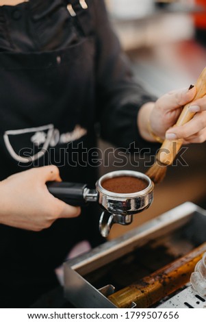 The process of making coffee step by step. Man tamping freshly ground coffee beans in a portafilter on a working wooden table