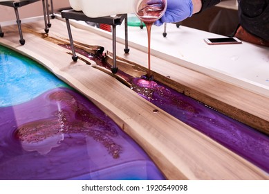 Process Making Of A Craft Resin And Wood Table. Liquid Epoxy Is Poured Into A Mold With Wooden Blanks. Closeup