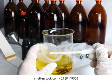 The Process Of Making The Essential Oil , Testing The Scent ,  Measure And Pour The Aroma Oil Into The Glass Black Bottles By A Perfumer In A Lab Before Making Air Room Freshener And Scented Candle