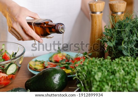 The process of making a healthy vegan salad with vegetables and microgreens. hand pours oil on food from reusable bottle. Vegetarian care for health and longevity. Nutritionist diet. cold pressed oil