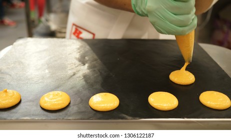 Process Of Making Macaron Macaroon, French Dessert, Squeezing The Dough Form Cooking Bag. Food Industry, Mass Or Volume Production.