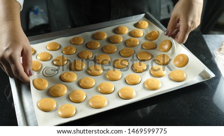 Process of making macaron macaroon, french dessert, squeezing the dough form cooking bag. Food industry, mass or volume production.