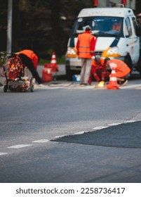Process of making new road surface markings with a line striping machine, workers improve city infrastructure, demarcation marking of pedestrian crossing with a hot melted paint on asphalt pavement