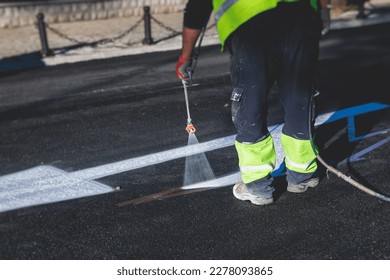 Process of making new road surface markings with a line striping machine, workers improve city infrastructure, demarcation marking of pedestrian crossing with hot melted paint on asphalt pavement
