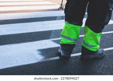 Process of making new road surface markings with a line striping machine, workers improve city infrastructure, demarcation marking of pedestrian crossing with hot melted paint on asphalt pavement
