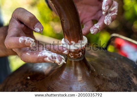 The process of making rakija brandy - Rakija is one of the most popular alcoholic drinks in Serbia. Hands that put a mixture of water and flour to seal the opening.