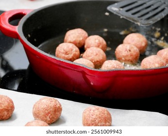 The process of making swedish meatballs. Raw meatballs cooking in a cast iron pan on the stove. Trasitional cuisine. Cooking in the kitchen. 