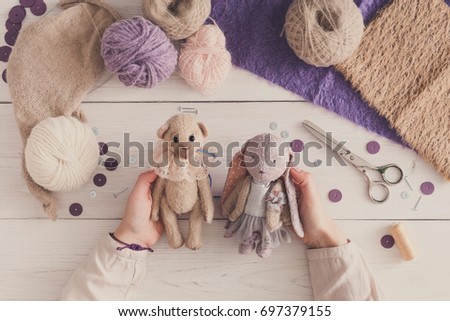 Process of making vintage toy, top view. Artisan pov, needlewoman hands holding handmade teddy bear and rabbit, home workshop