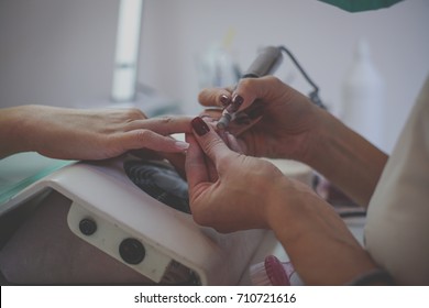 The process of manicure at nail salon with electrical  file.  Close up.