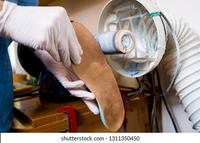 The process of manufacturing orthopedic individual insoles for people with leg diseases, flat feet. Close-up of a man's hand of an employee urges an orthopedic insole on a machine tool in a workshop.