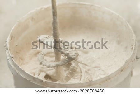 the process of mixing plaster mortar putty mixer in a bucket close-up