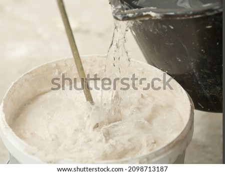 the process of mixing plaster mortar putty mixer in a bucket close-up