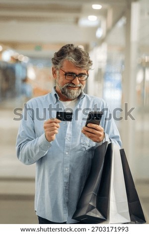Process of online payment by using credit card and smartphone. Senior man is in the mall, shopping time conception.