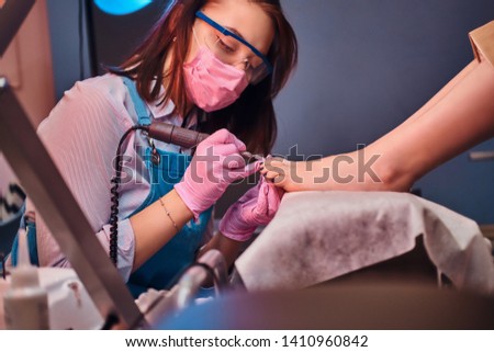 Process of pedicure at busy nail studio. Customer is getting good service from beautiful diligent master.